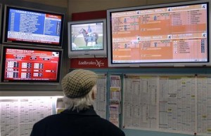 A man watches television screens in a Ladbrokes bookmaker in London